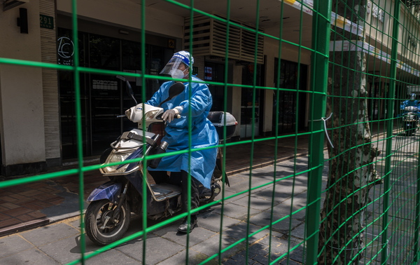 25일 중국 상하이에서 격리 지역 주민들의 외출을 막기 위해 최근 설치된 녹색 철조망 옆으로 스쿠터 탄 남성이 지나가고 있다. 상하이에서는 코로나19 확산 방지 대책으로 지난달 28일 이후 사실상의 전면 도시봉쇄가 계속되고 있다. /EPA=연합