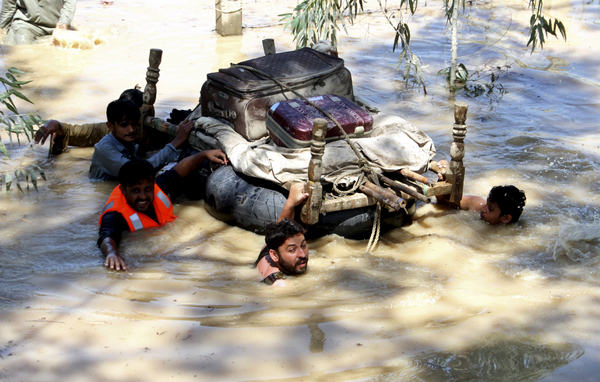 28일(현지시간) 파키스탄 페샤와르 외곽의 침수 지역에서 홍수 피해를 입은 사람들이 살림을 띄워 이동시키고 있다. /AP=연합