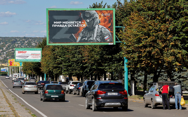 20일(현지시간) 러시아군이 점령한 우크라이나 동부 루한스크 거리에서 차들이 친러시아 구호가 적힌 옥외 광고판을 지나고 있다. /로이터=연합