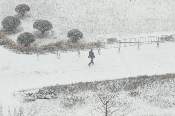 서울을 비롯한 중부지방에 대설주의보가 내려진 15일 서울 종로구 열린송현녹지광장에서 시민이 내리는 눈을 맞으며 이동하고 있다. /연합