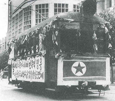 1950년 6월 28일 북한의 침략으로 인민군에게 서울이 점령당하자 많은 사람들이 몰려나와 '인민군 환영' 현수막을 단 전차를 타고 서울시내를 달리는 모습.