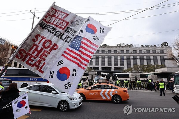 지난 2월 25일 헌법재판소 앞에서 한 시민이 윤석열 대통령 탄핵반대를 외치며 깃발을 흔들고 있다. 윤 대통령 탄핵에 반대하는 국민은 이미 과반수를 넘겼다. /연합