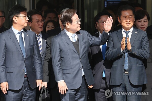 지난 26일 오후 공직선거법 위반 항소심에서 무죄 판결을 받은 이재명 더불어민주당 대표가 청사 앞에 도열하고 있던 민주당 의원들을 향해 손을 흔들고 있다. 그는 무죄 판결 이후 시종 여유로운 표정을 보였다. /연합