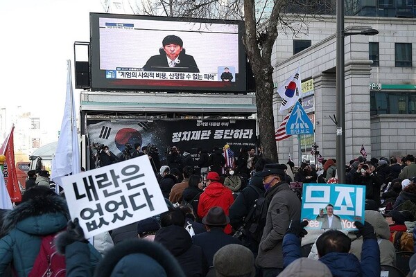 12·3 비상계엄과 관련해 기소된 윤석열 전 대통령에 대한 1심 선고가 열린 19일 서울 서초구 서울중앙지방법원 인근에서 지지자들이 관련 뉴스를 보고 있다. /연합